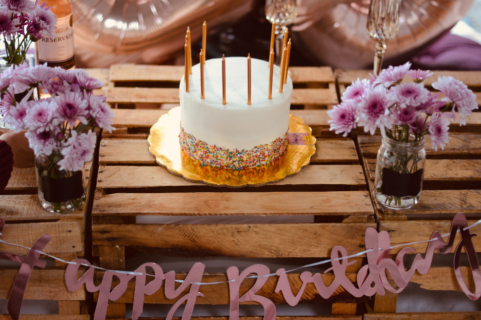 A birthday cake topped with candles with a streamer that reads Happy Birthday.