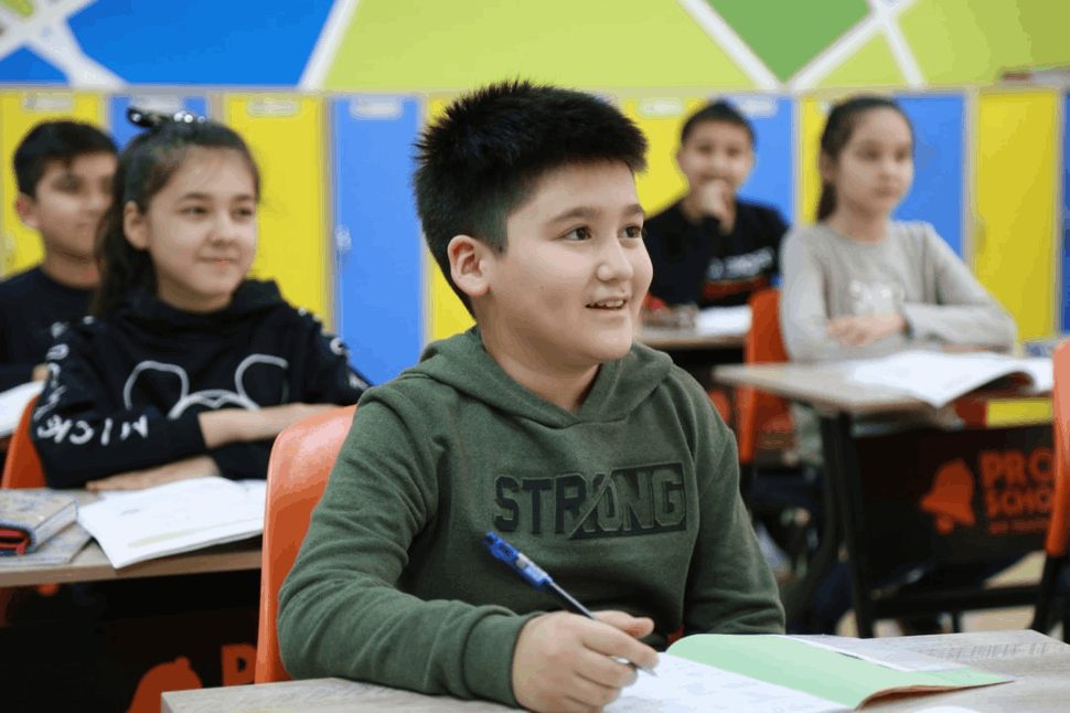 A boy in a green long sleeve shirt holding a pen.