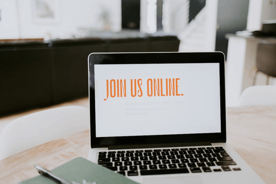 a Macbook pro with JOIN US ONLINE text on screen is placed on a table