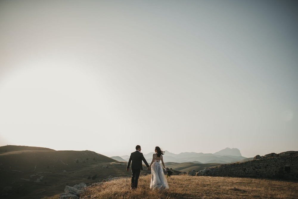 Photo of a bride and groom on a hilll, over looking beautiful scenery.