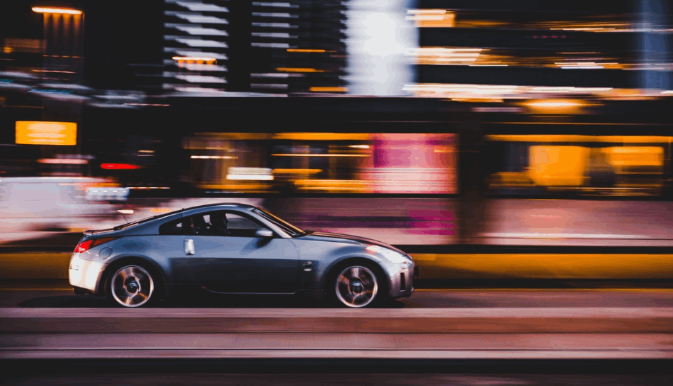 panning photography of silver nissan 370z on a city street.