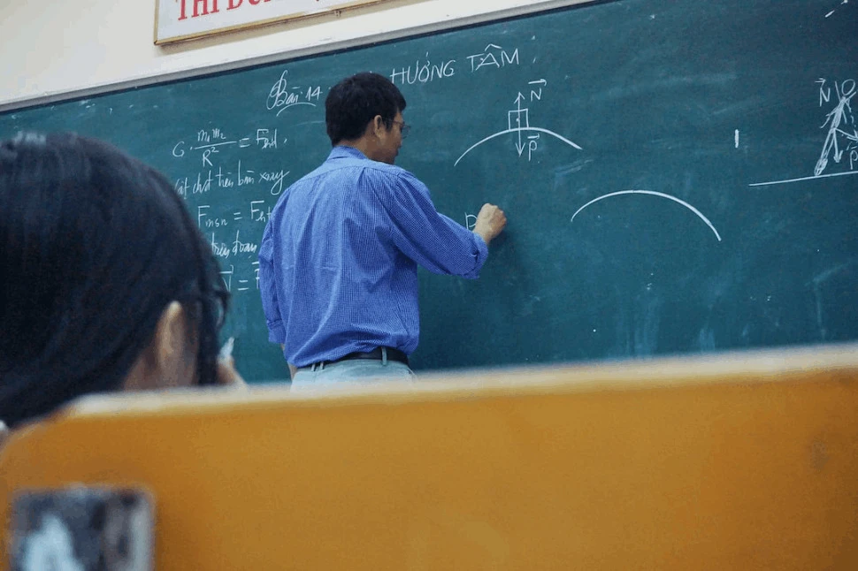 teacher teaching mathematics while writing and drawing figures on the blackboard
