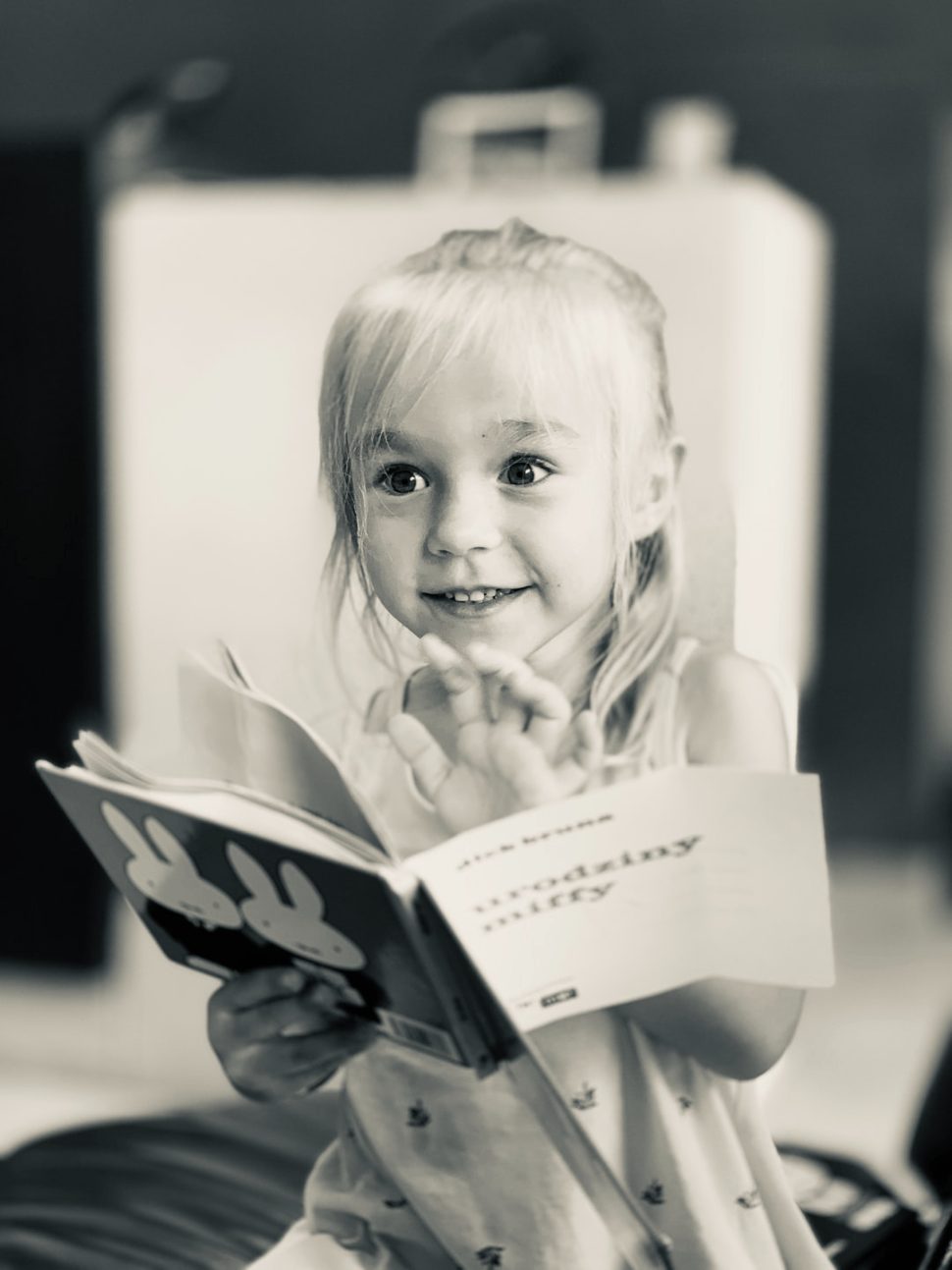 A young girl happy to be reading because she understands basic concepts in the book.