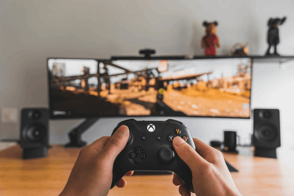 hand holding gaming pad in front of big television screen 