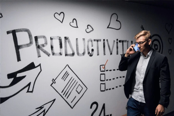 a man holding smartphone looking at productivity wall decor