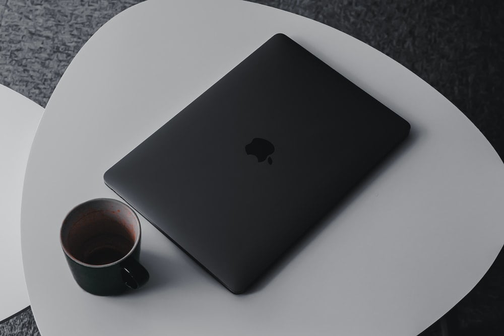Grey mug and Macbook pPo on a white table. 