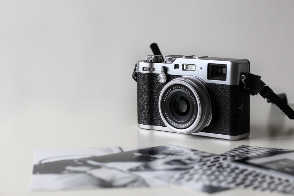 A black and gray film camera near printed photos