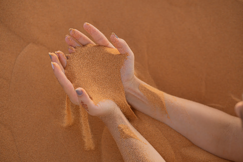 A person holding a handful of sand from the desert.