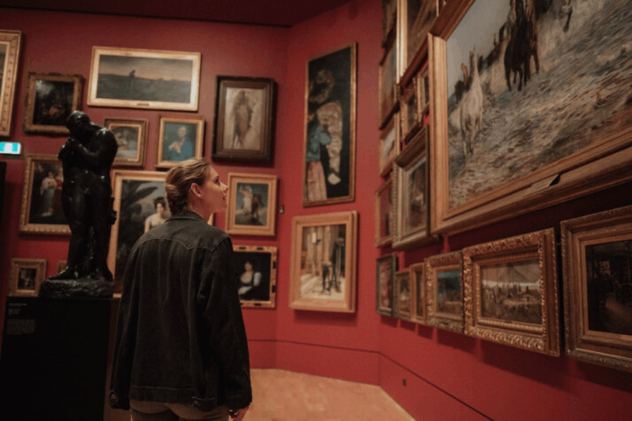 a person looking at painting collection on the wall