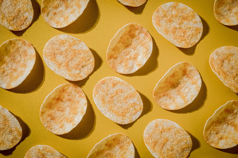 Potato chips that are arranged neatly on a yellow surface.