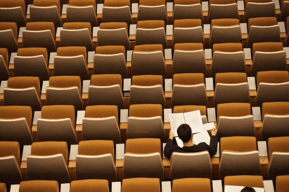 a student in a lecture hall studying by himself.