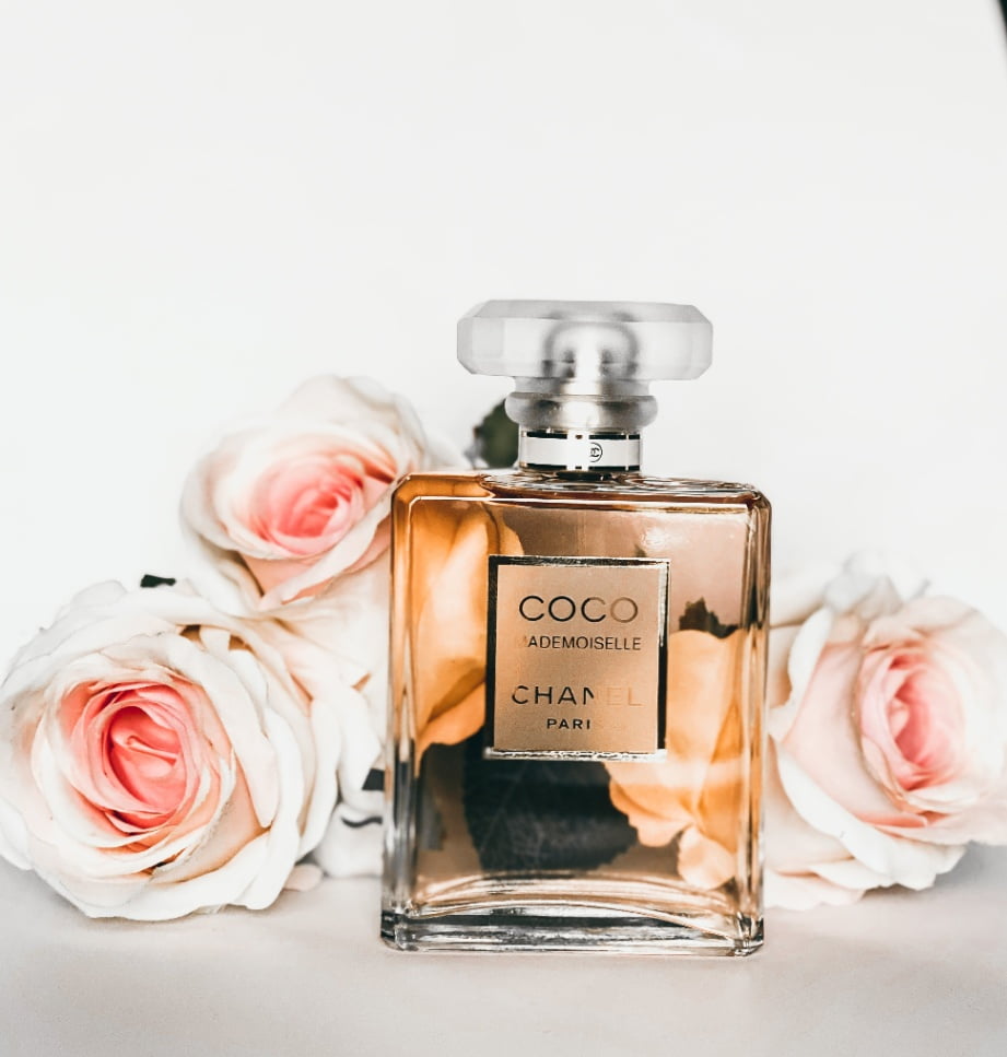 A Chanel perfume bottle with roses on a white surface.