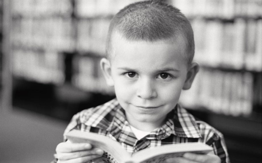 In a timeless black and white photograph, a young boy is captured with a book, embracing the joy of reading.