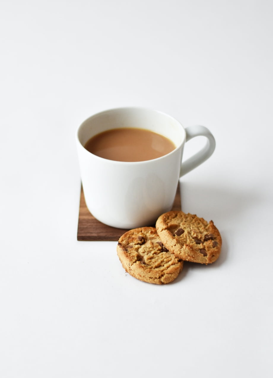 tea with milk in a white mug and two biscuits.