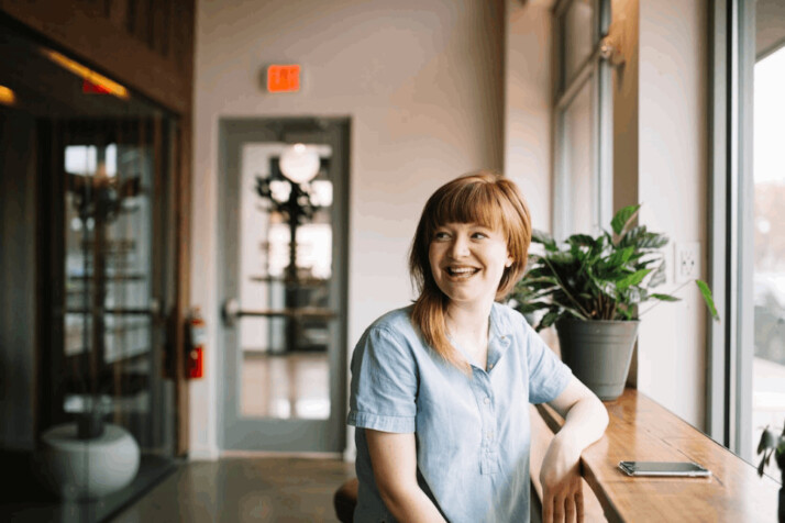 a woman sitting in front of brown wooden table