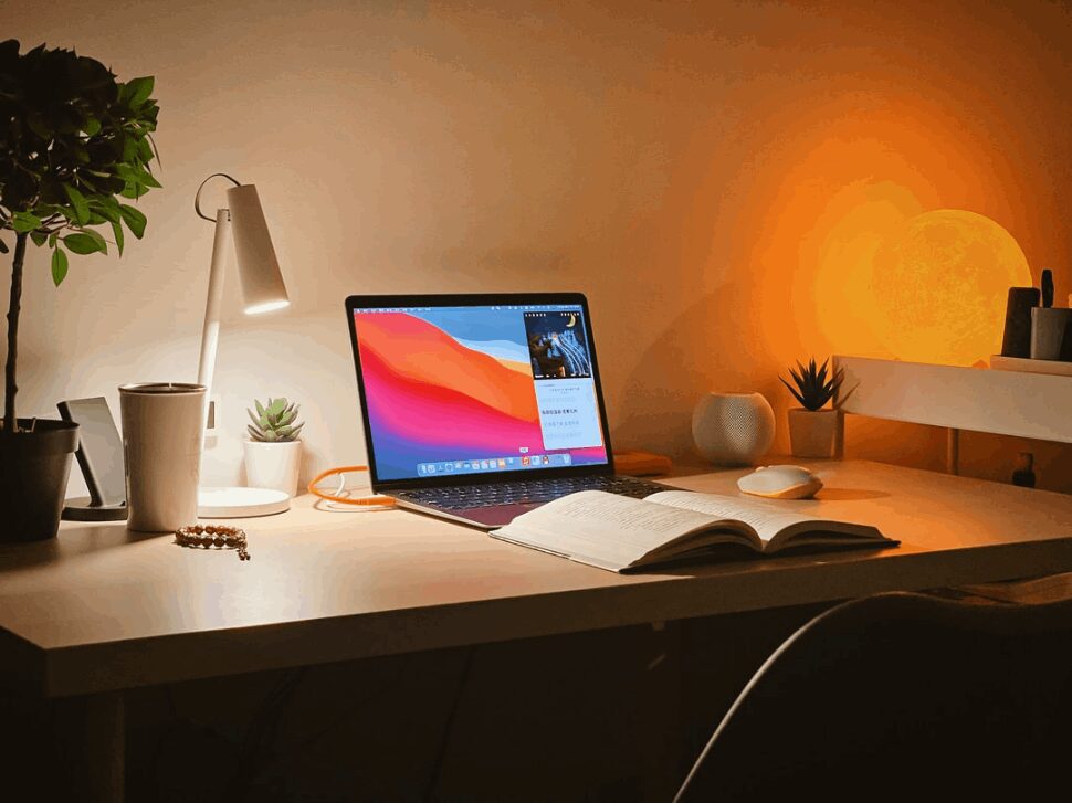 A laptop with a colorful wallpaper, placed on top of a wooden desk.