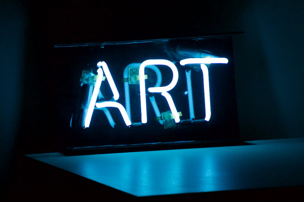 An Image of a neon sign saying "ART" in a dark room