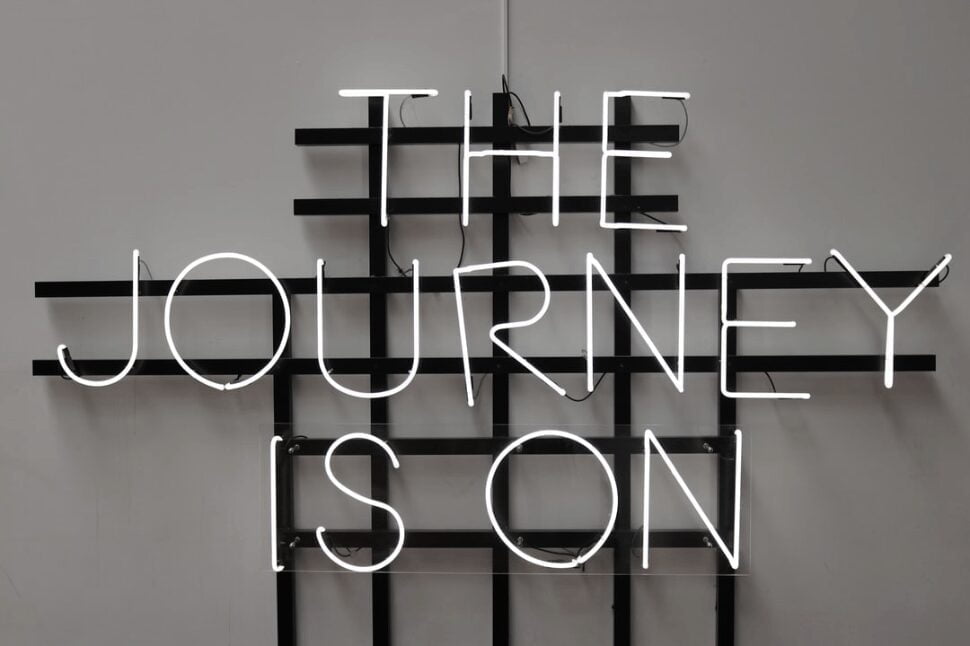 The Journey is On LED signage on a black metal frame.