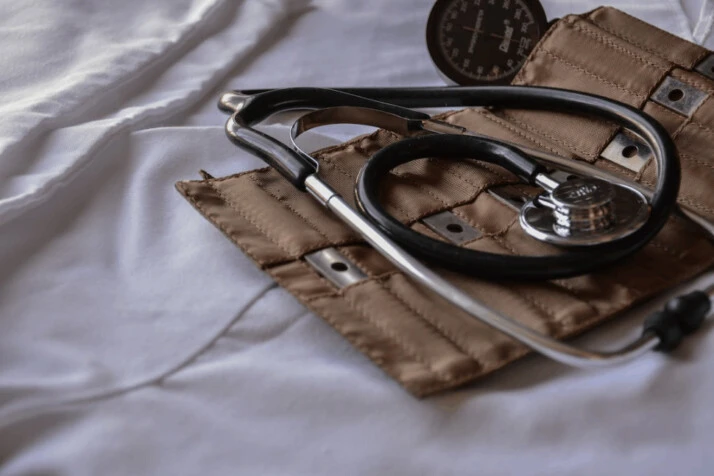 a black stethoscope placed over a brown leather case