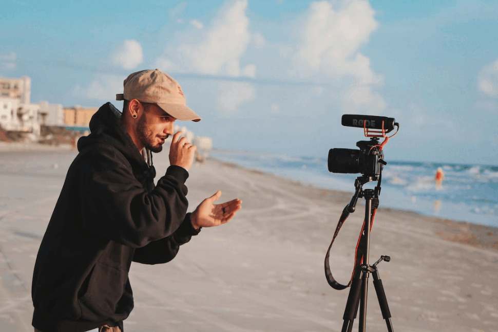 man in black jacket holding camera during daytime on a beach