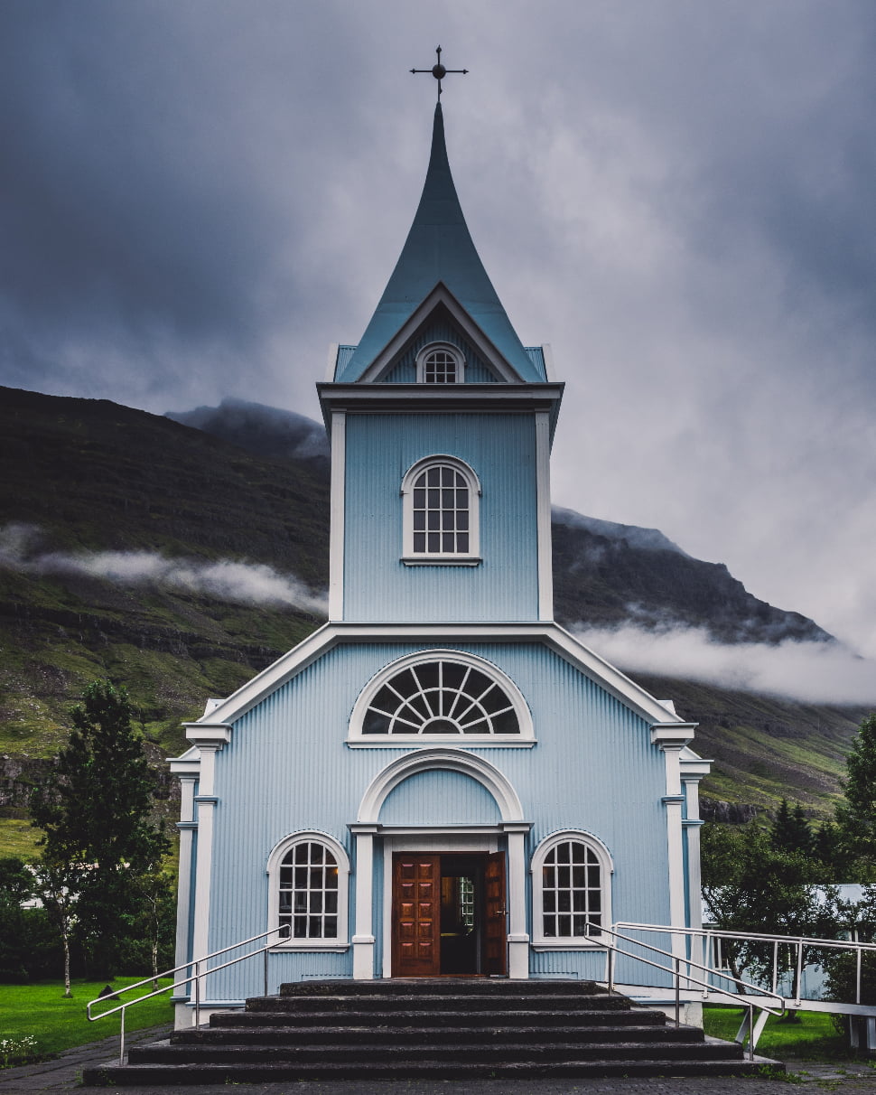 a light blue church in front of a mountain in Iceland.