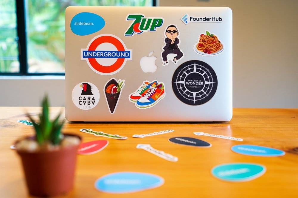 Laptop full of stickers from different brands and personalities.