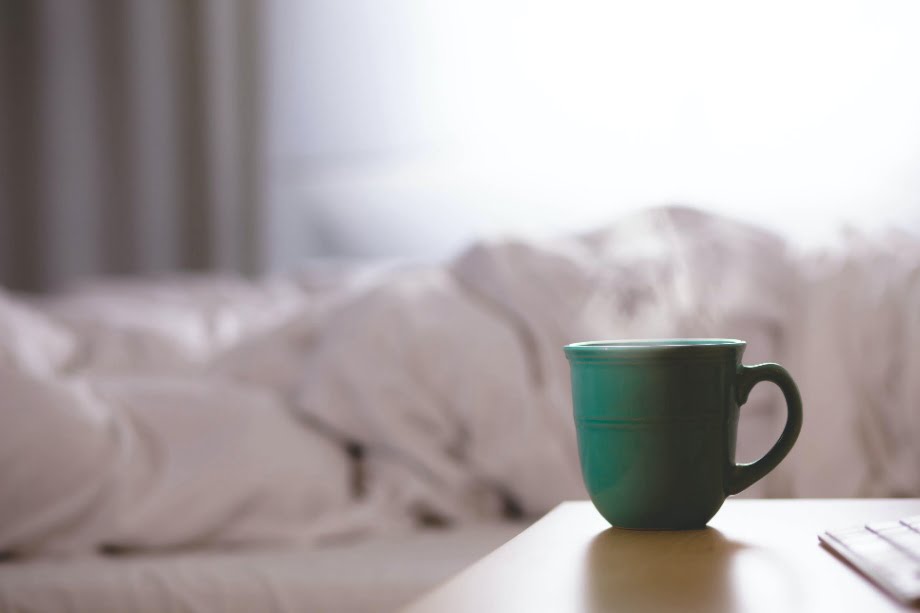A green cup of coffee placed on a bedside table.