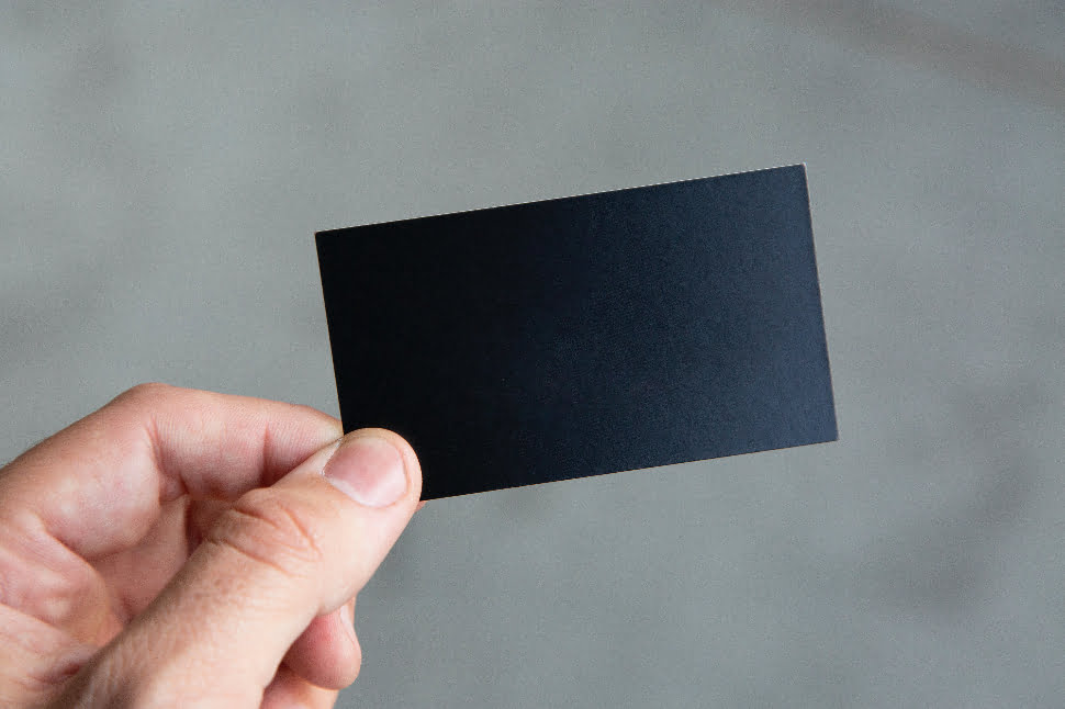 Blank business card held between the thumb and index finger
