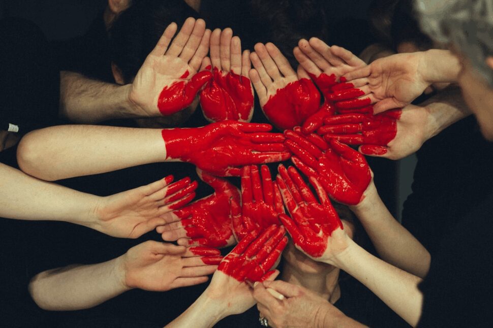 Several pairs of painted hands joined together to form a heart.