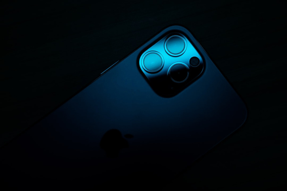 An iPhone 13 under a black and blue light.