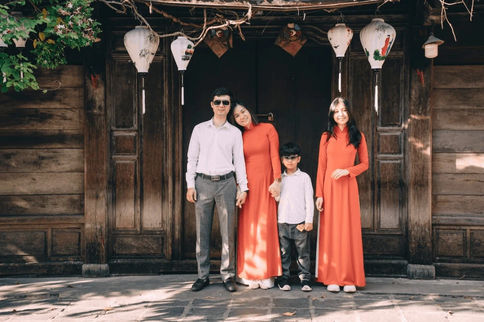 An East Asian Family in front of a wooden door.