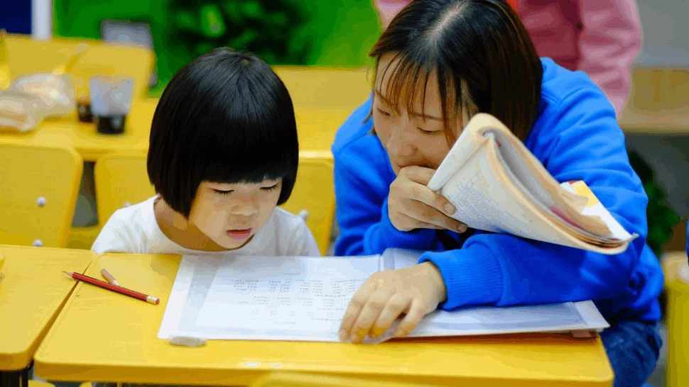 A teacher helping a child with reading comprehension to develop her skills.