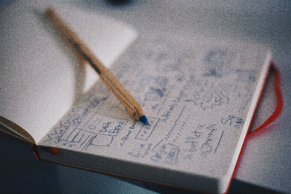 A pen placed in between the pages of a book with sketches