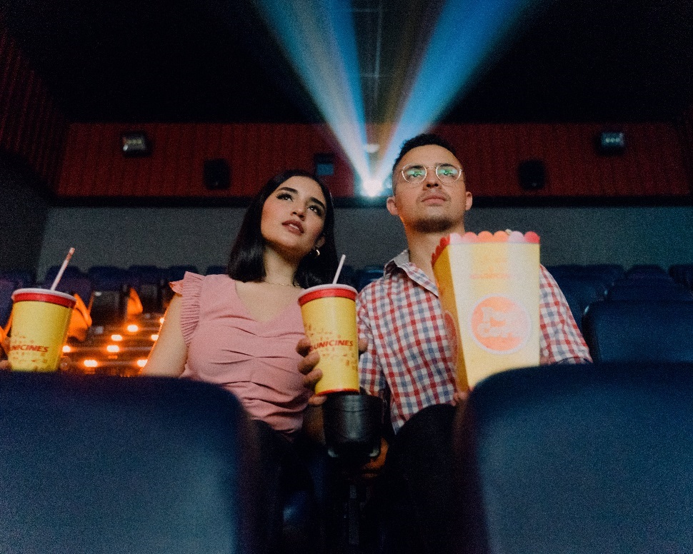 Two individuals enjoying a movie in a theater