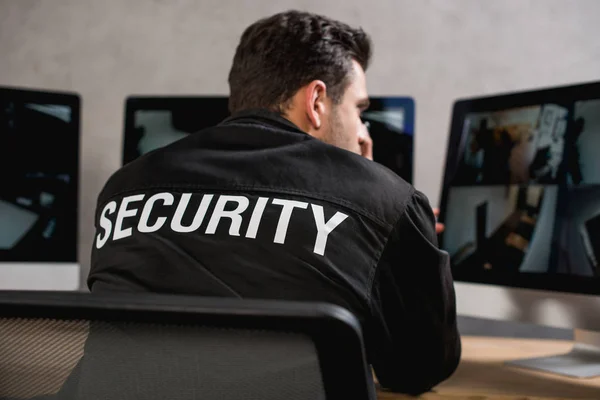 man wearing black security uniform and sitting in front of computer
