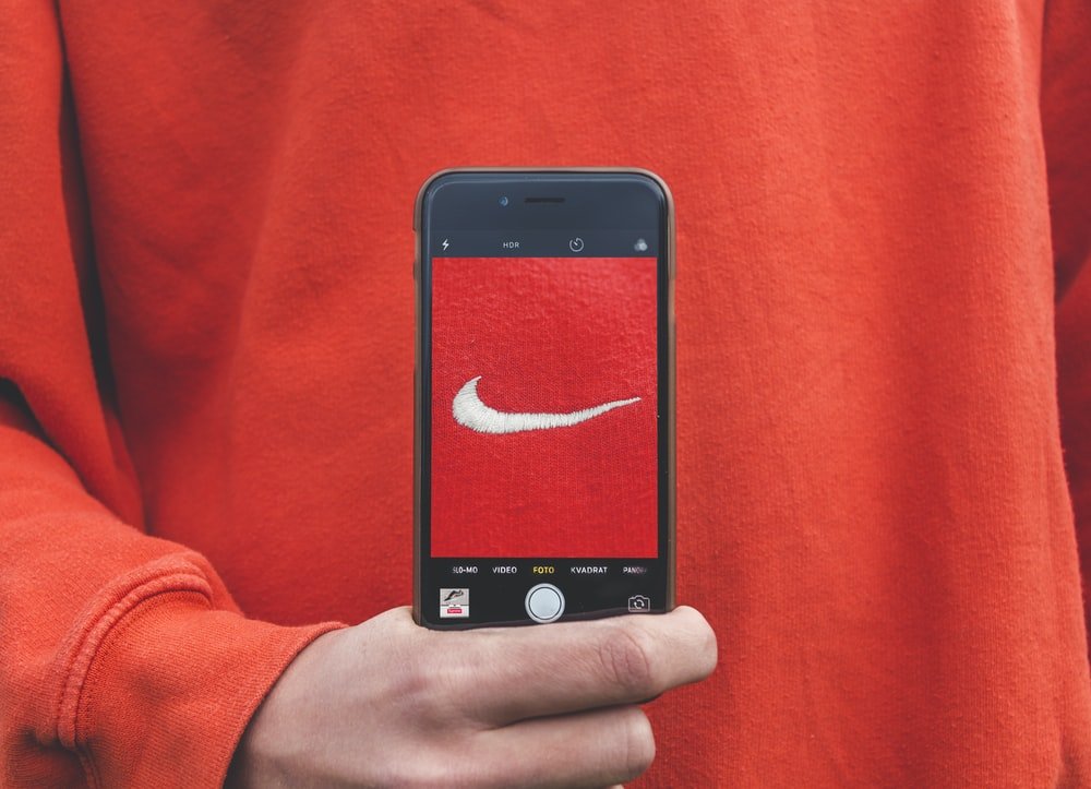A person holding iPhone taking picture on Nike label