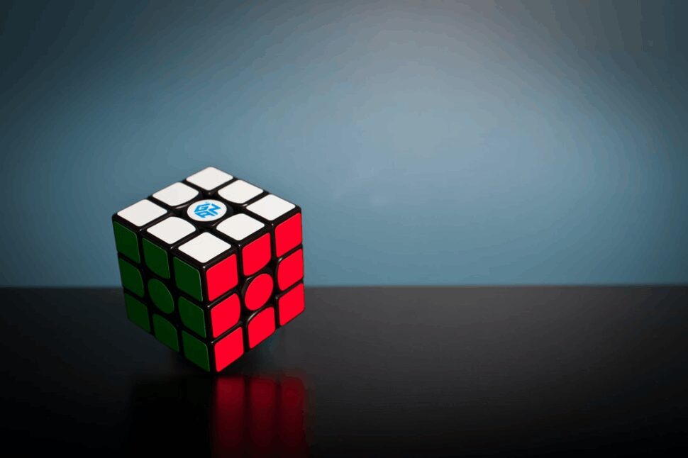 A solved 3x3 Rubik's Cube placed on a black surface. 