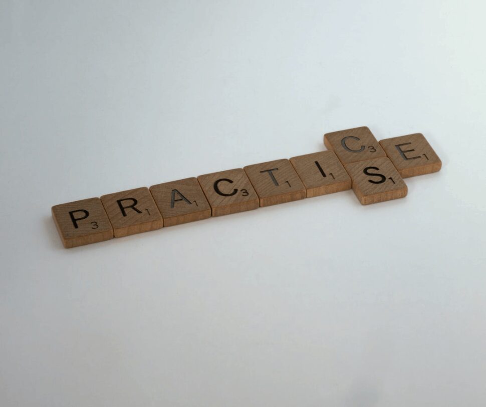 PRACTICE brown wooden scrabble blocks on a white surface.