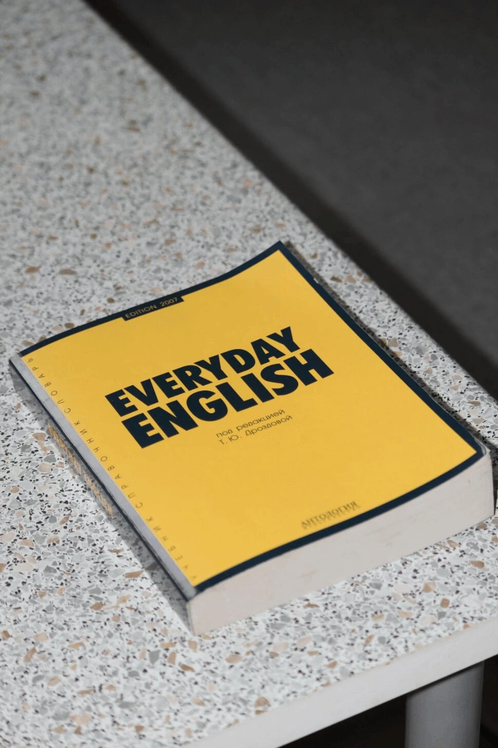 Everyday English book that's color yellow and lays on top of a concrete table.