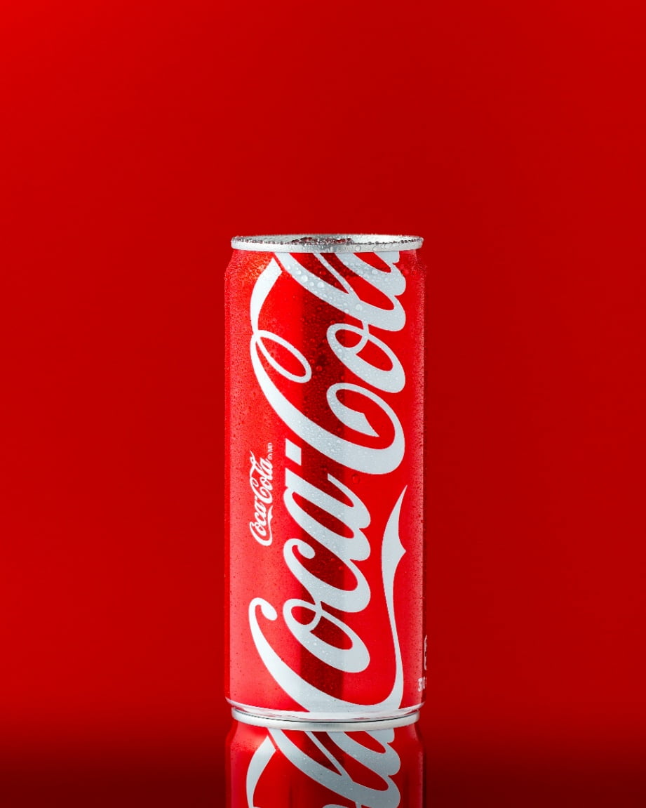 A cold Coca-Cola can pictured against a red background.