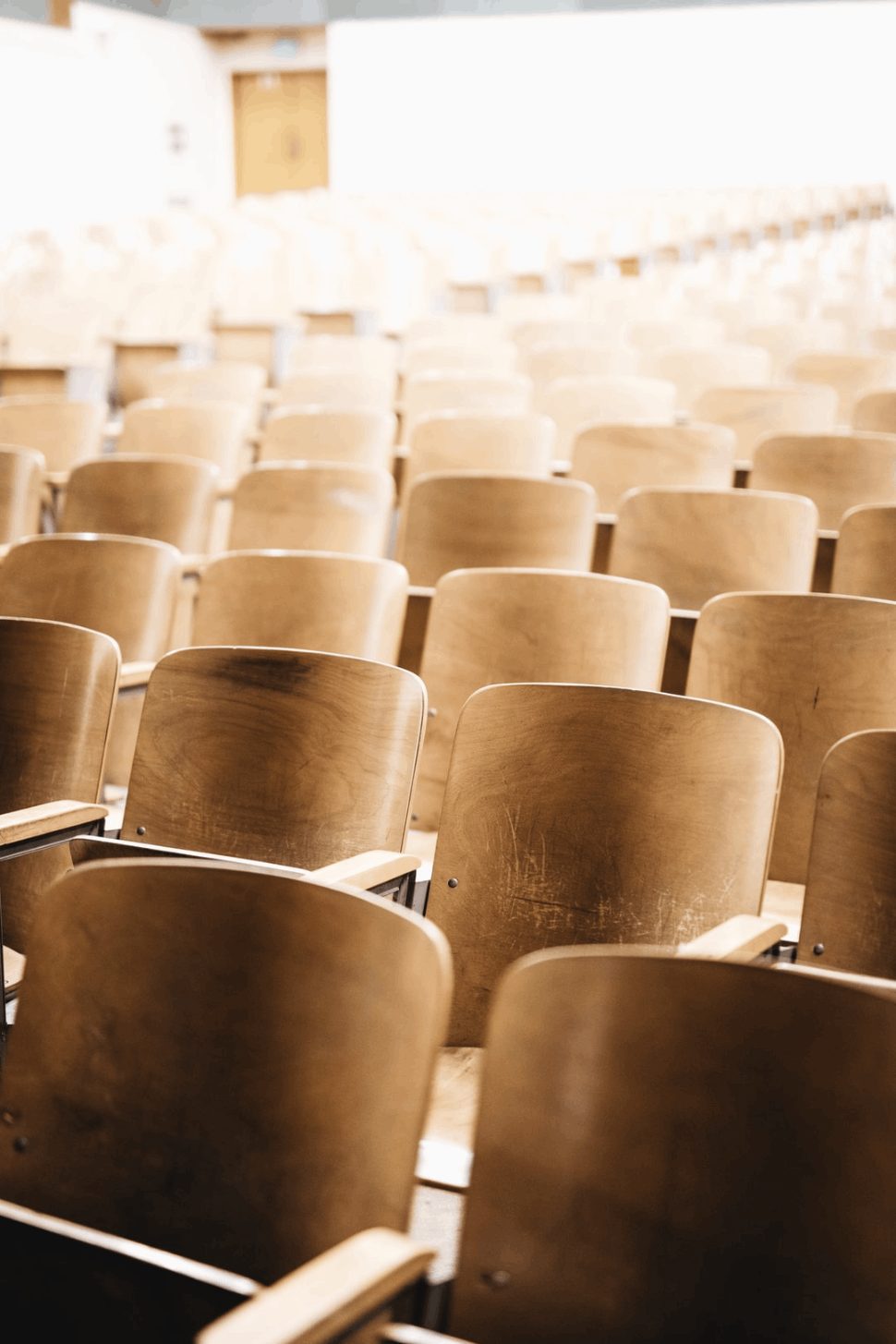 vacant brown wooden chairs at a lecture hall of an university