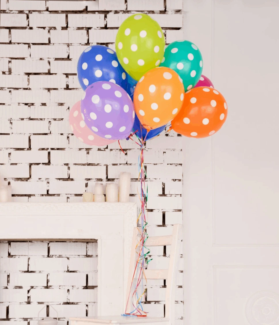assorted-color polka dot balloons close in white walled room