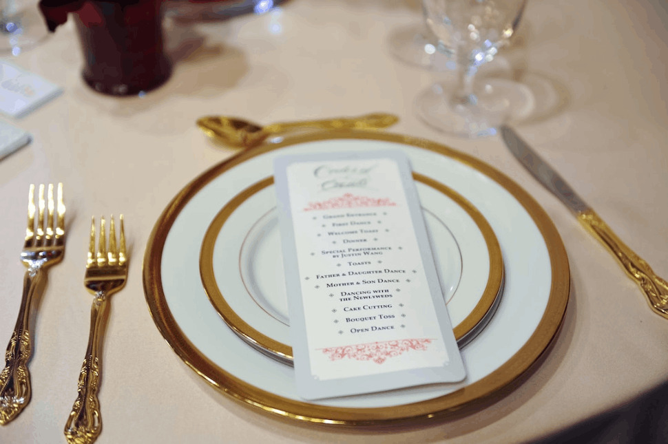 wedding program on white and gold round plate on table