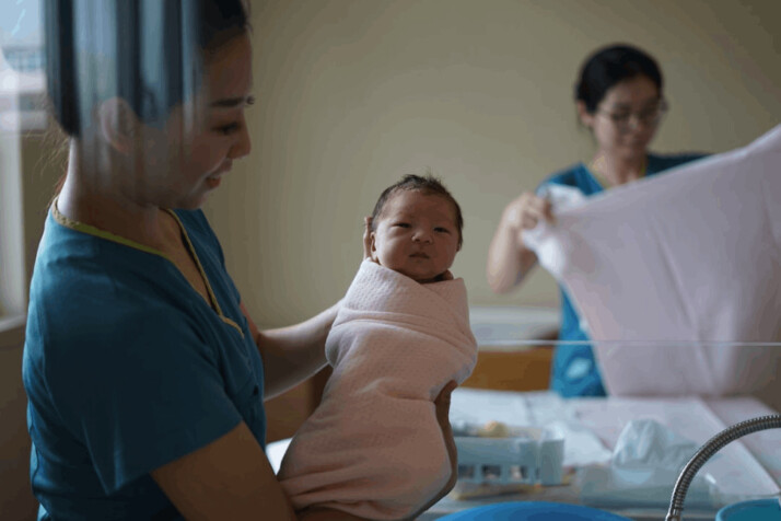 a woman carrying a newborn baby at the hospital