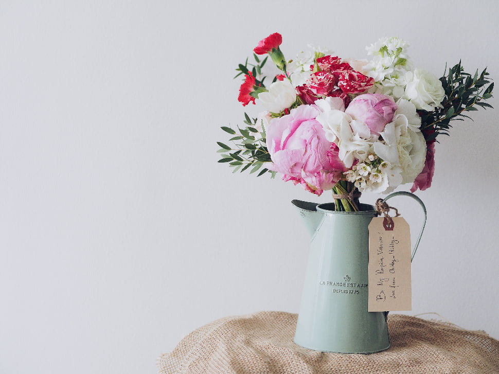 A beautiful arrangement of flowers placed in a kettle vase.