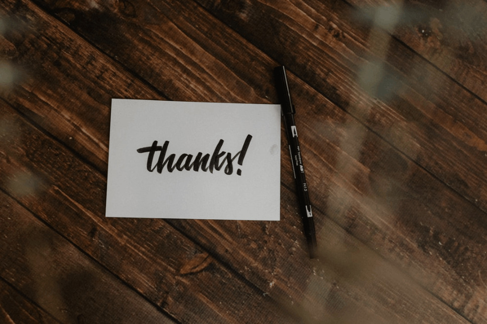 thank you note paper and black pen on wooden table 