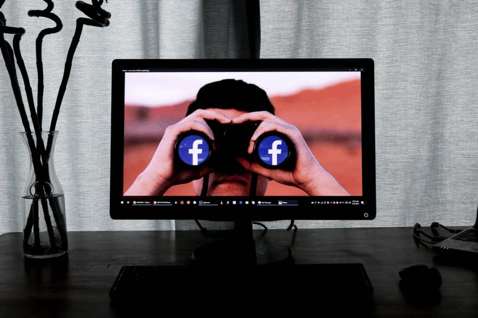 A television showing a man using binoculars with Facebook icon on the lens.