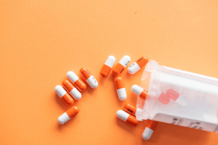 orange and white medication pills over a pale orange background