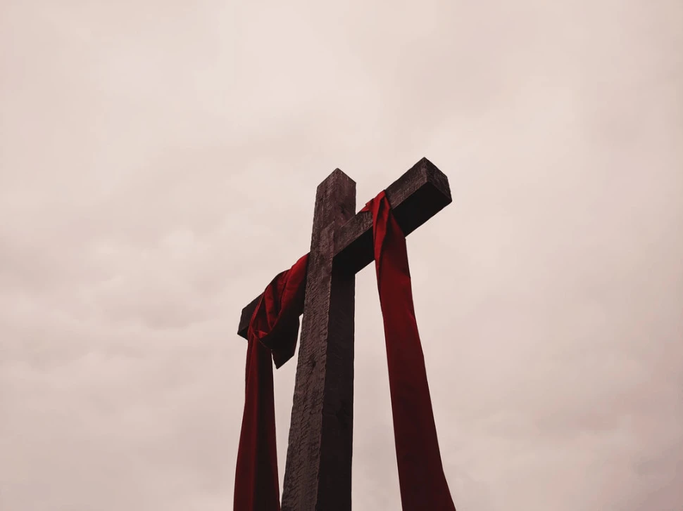 low angle view of cross with red garment showing dark skies