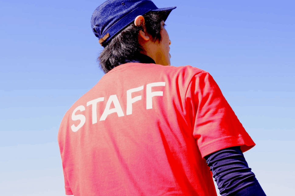 male staff wearing red t-shirt and blue hat standing